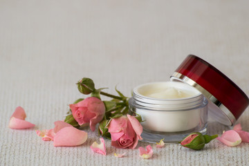 Fototapeta na wymiar Natural cosmetic. Fresh tender rose petals and a small round jar with cream for skin care of face and body on a light background. 