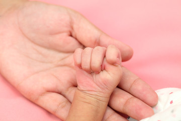 Obraz na płótnie Canvas Mother holding newborn baby's hand-New life care