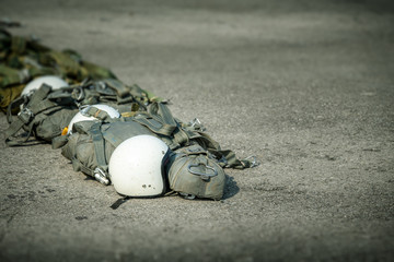 row of T-10 tactical parachute bag with parachute reserve and helmet on ground prepare for...