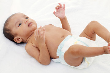 Playful newborn baby lying down in bed