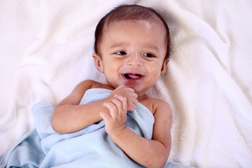 Playful newborn baby lying down in bed