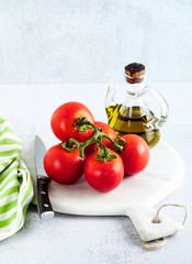 a branch of fresh ripe wet tomatoes and olive oil on a table made of stone.