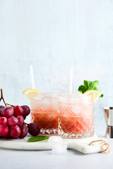 pink alcoholic cocktail of fresh ripe grapes in a shaker with ice, lemon and mint. summer refreshing drink on the table