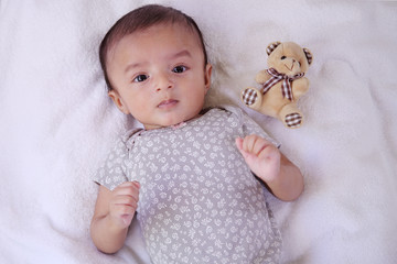 Newborn baby boy with teddy bear on bed