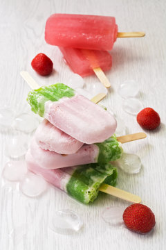Strawberry ice cream on a stick. A stack of ice cream is pinkish green.A stack of ice cream is pinkish green.