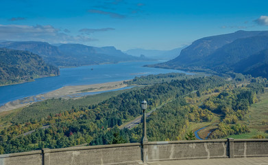 Fototapeta na wymiar Columbia River Highway, Corbett in Oregon, USA - October 12, 2015: Panoramic from the viewpoint over the Columbia River gorge, with a streetlight on the wall on a sunny day