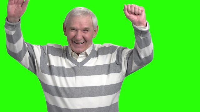 Portrait of laughing granddad, slow-motion. Happy laughing grandpa putting hands up against green hromakey background.