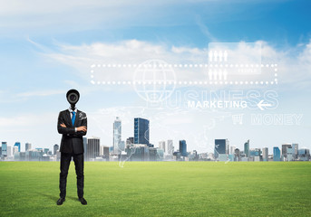 Camera headed man standing on green grass against modern cityscape