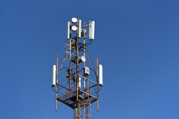 Antennas for cellular and mobile communication on a tower on a blue sky background