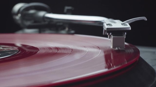 Pressing play and turning on the vintage turntable player with red vinyl