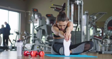 A beautiful woman is stretching after finishing her workout and stretching her muscles to avoid getting hurt. Concept of: fitness, yoga, health. - Powered by Adobe