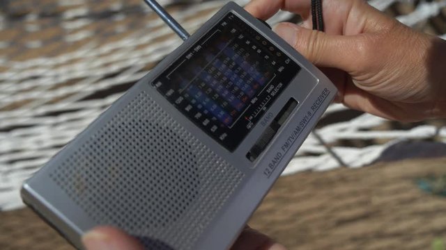 A woman surfing through stations on a vintage transistor radio