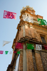 Looking up at the side of the clock tower of Our Lady of Guadalupe with colored flags in foreground in Puerto Vallarta, Mexico