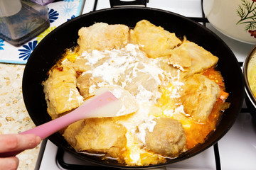 Woman stew meat stuffed cabbage in tomato sauce with sour cream.