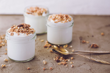 Yoghurt with granola made of oats, raisins, puffed rice, chocolate and dried bananas. Healthy breakfast for family.