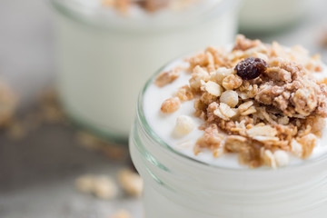 Yoghurt with granola made of oats, raisins, puffed rice, chocolate and dried bananas. Healthy breakfast for family.