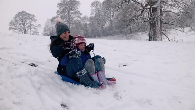 Mother and son sharing a sledge on a snowy hillside