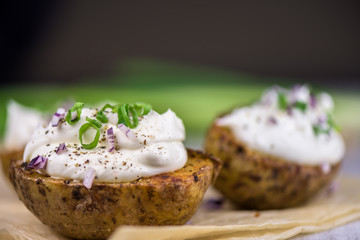 Baked potatoes with curd white cheese, red onion and chive - closeup