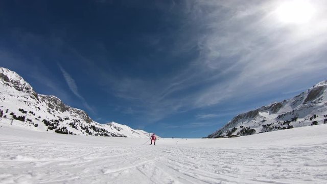 4K winter sport video one cross country skier in race suit skating on cross country ski run on sunny winter day with blue sky in mountains
