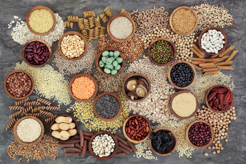 Dried macrobiotic health food with grains, cereals, pulses, nuts, seeds and whole wheat pasta. Super foods high in smart carbohydrates, protein, antioxidants and fibre on marble background top view.