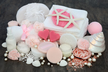Luxury beauty and spa treatment products including pink heart shaped soaps, ex foliating salts, sponges, flannels, moisturising cream, body lotion, powder puffs, flowers, decorative shells and pearls 