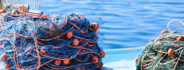 Stacks of fishing nets on blue sea water background. Marsaxlokk port, Malta