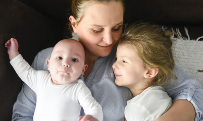 Young mother hugging two little children