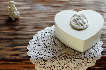 white jewelry box with angel ornament on wooden background, present or decoration