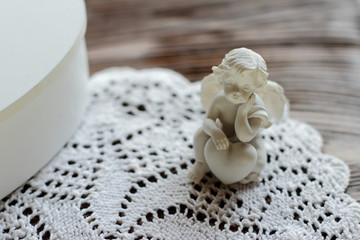 Fototapeta na wymiar little cute angel on knitted napkin on wooden table, romantic decoraton, vintage