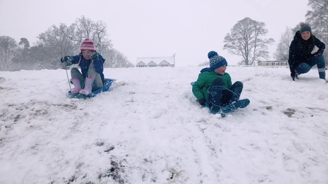 Brother and sister having a sledge race and the girl gets wiped out