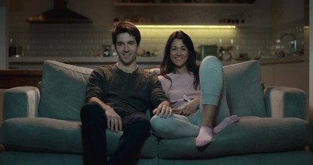 Happy couple enjoying a cozy night in on the sofa watching tv - Powered by Adobe