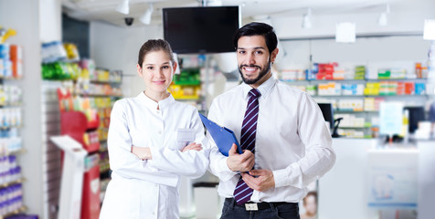 pharmacist and expert standing near shelves with medicines