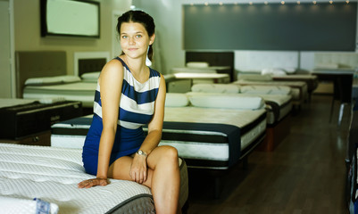 Young girl sitting at new mattress and smiling