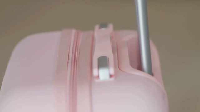 Detail shot of a female hand pulling a pink suitcase handle, 4k slow motion