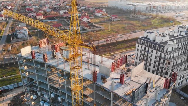Construction site with a bird's eye on the Sunset. Video shooting with drone. New house near the road and shopping center. Flying over the construction site. The construction of the plant in the city.