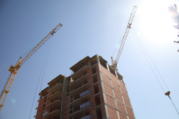 Naklejka premium Construction site with cranes on sky background. Construction of a residential multi-storey building. New residential area