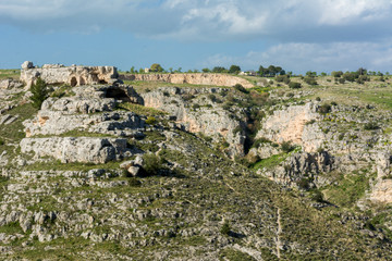 Fototapeta na wymiar Horizontal View of some Prehistoric Caves in the Gravina of the Sassi of Matera on Blue Sky Background. Matera, South of Italy