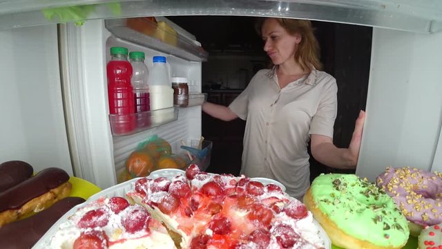 Woman opens the refrigerator at night. night hunger. diet. gluttony, 4k