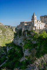 Vertical View of the Church of Peter and Paul Saints on the Background of the Caves of the Gravina of Matera on Blue Sky Background. Matera, South of Italy