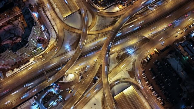 Aerial hyperlapse shooting of a busy multilevel  junction. Illuminated highway from the bird's eye view.  Car light trails at night.