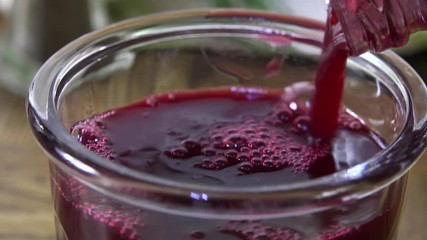 Pouring cranberry juice into a glass slow motion - Powered by Adobe