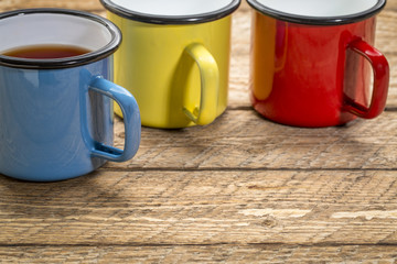 metal cups of hot tea on a rustic picnic table