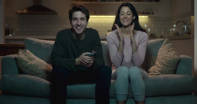 Young couple sitting on a sofa excited to be watching their favourite movie.