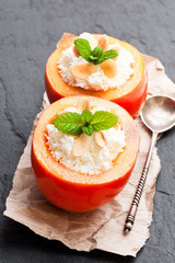 Sweet  persimmons stuffed with cottage cheese and almonds on black stone background