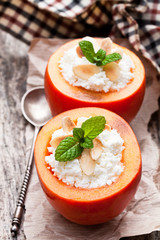 Sweet  persimmons stuffed with cottage cheese and almonds on wooden table