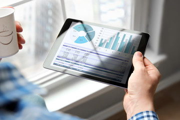 Business man working and analyzing financial figures on a graphs on a tablet  in  the office