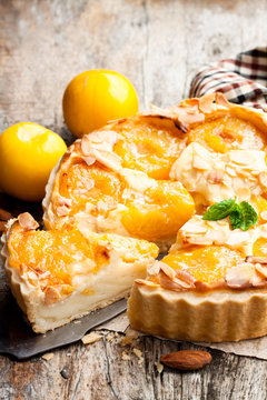 Delicious  tart with yellow plum and almonds on wooden table