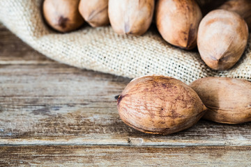 pecan nuts on wooden table with pecans in gunny sack background, close up shot
