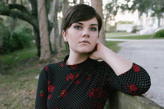 Cute Female Model With Pixie Hair Cut Posing On Green Bench Outside