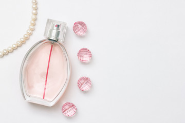 Bottle of parfume. Pearl necklace, pink crystals and place for a simple text on a light white background.